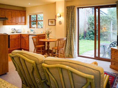 a kitchen with a table and chairs and a dining room at Honeysuckle Cottage in North Mundham