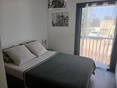 a bedroom with a bed and a large window at charmante maison neuve proche plage et commerces in Calvi
