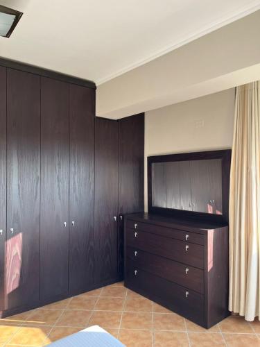a bedroom with wooden cabinets and a dresser at Orikum Apartment in Orikum