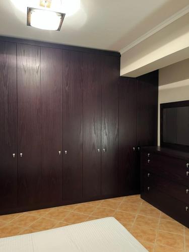 a room with wooden cabinets and a flat screen tv at Orikum Apartment in Orikum