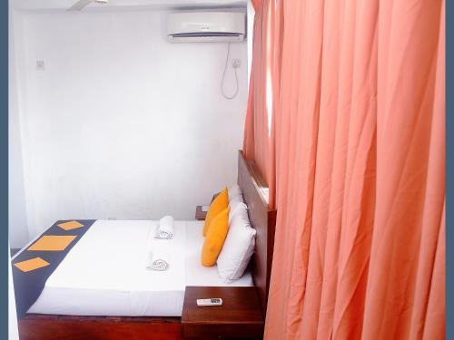 Dormitorio pequeño con cama con cortina naranja en 256 Townhouse Rest, en Kandy