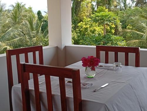 a white table with a vase of flowers on it at Ocean Bliss Beach Resort in Pongwe