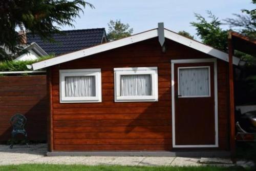 een klein huisje met een deur en twee ramen bij Kleines Haus Mit Garten, Direkt Hinter Dem Deich in Baarland