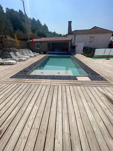 a swimming pool with a wooden deck and a house at Gabriela Olival turismo 
