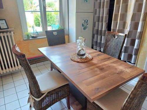 a wooden dining table with chairs and a vase on it at L'étoile du matin in Terville