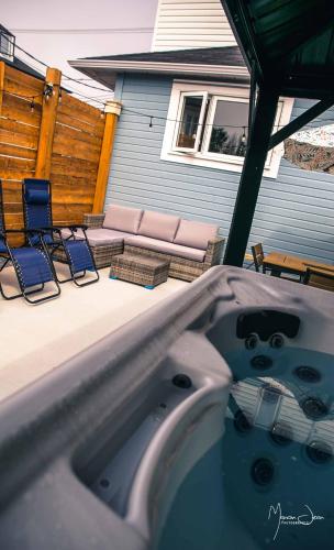a hot tub in a backyard with chairs and a patio at Spa & Pool Table - Le Parvis in Trois-Pistoles