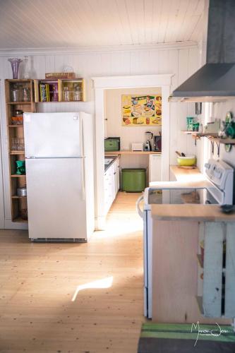 a kitchen with a white refrigerator and a wooden floor at Spa & Pool Table - Le Parvis in Trois-Pistoles