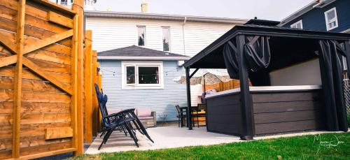 a patio with a black cover next to a house at Spa & Pool Table - Le Parvis in Trois-Pistoles