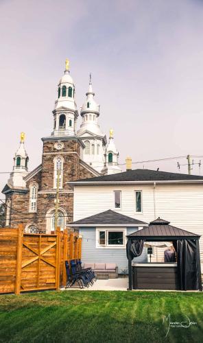 a church with a fence and an umbrella in front of it at Spa & Pool Table - Le Parvis in Trois-Pistoles