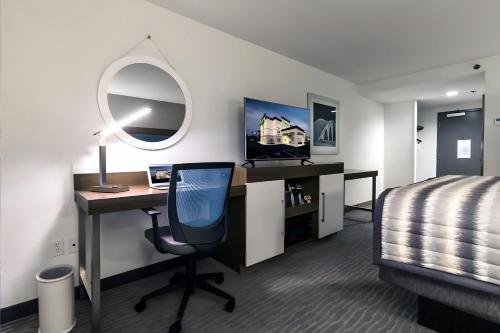 a bedroom with a desk and a bed and a mirror at Wingate Augusta Washington Road by Wyndham in Augusta