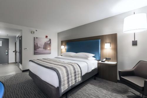 a hotel room with a large bed and a chair at Wingate Augusta Washington Road by Wyndham in Augusta