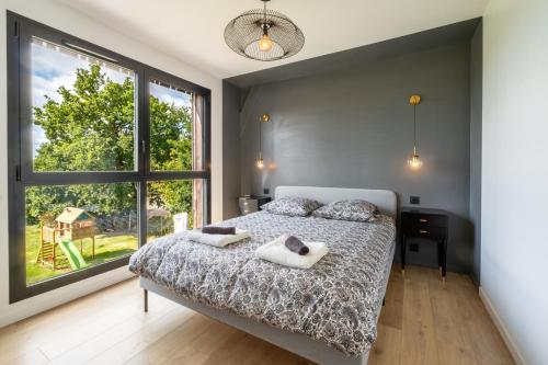 a bedroom with a bed and a large window at Maison d'architecte au coeur de la nature in Guichen