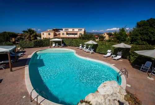 a large swimming pool with chairs and umbrellas at Hotel Raffael in Putzu Idu