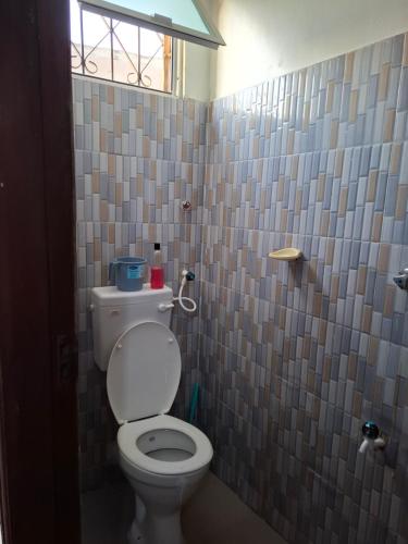 a bathroom with a toilet and a tile wall at Studio Apartment Naivas Mwembe tayari Cbd in Mombasa