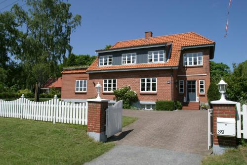 a red brick house with a white fence at Kollund Rooms in Kollund Østerskov