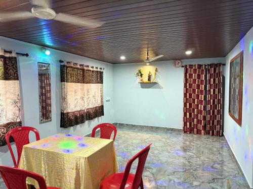 a dining room with a table and red chairs at Braganza Home Stay honnavar in Honāvar
