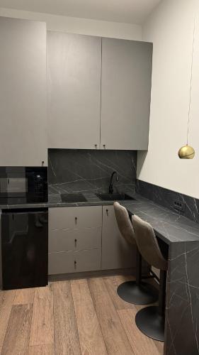 a kitchen with white cabinets and a black counter top at Unirii Residence in Cluj-Napoca