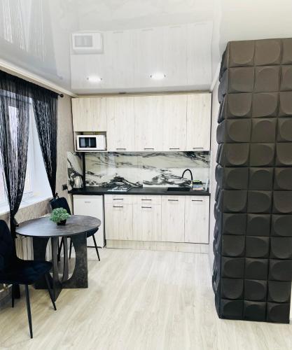 Студия 3-х комнатная ул Соборности 42 في كريفوي روغ: مطبخ مع دواليب بيضاء وطاولة في الغرفة