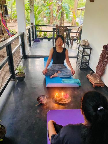 a woman sitting on the floor in a meditation pose with a candle at Zensigiri Ayurveda Wellness Homestay in Sigiriya