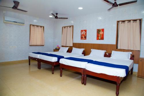 two twin beds in a room with two windows at SR Residency in Chennai