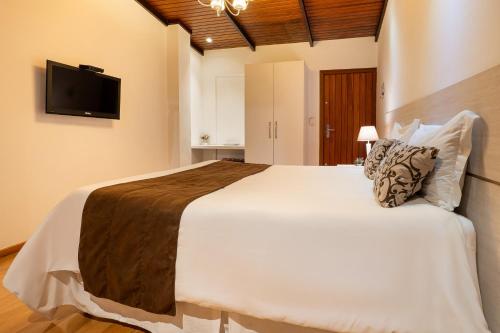 a bedroom with a large bed and a tv on the wall at Pousada Apple House Campos do Jordao in Campos do Jordão