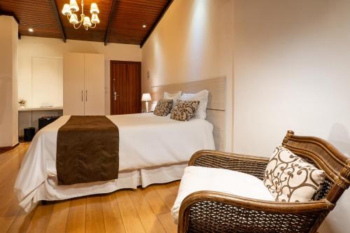 a bedroom with a bed and a wicker chair at Pousada Apple House Campos do Jordao in Campos do Jordão