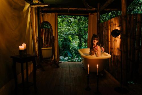a woman sitting in a bath tub in a bathroom at Colina Secreta - Glamping and Villas in Puerto Viejo