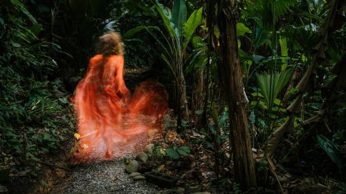 a woman walking down a path in the jungle at Colina Secreta - Glamping and Villas in Puerto Viejo