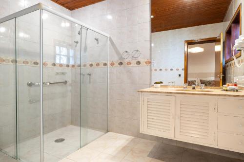 a bathroom with a glass shower and a sink at Pousada Apple House Campos do Jordao in Campos do Jordão