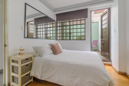 a bedroom with a white bed and a mirror at Senda Stays Condesa in Mexico City