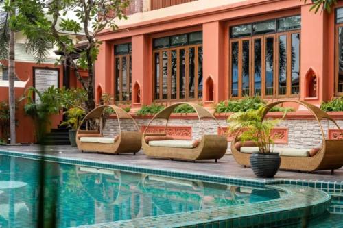 a pool with chaise lounge chairs next to a building at Sunday Chateau En Ville - Pattaya in North Pattaya