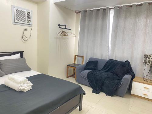 a bedroom with a bed and a chair and a window at Cozy Room in Modern Paraaque Condo with 2 Bedrooms in Manila