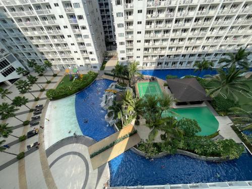 an aerial view of a pool with palm trees and buildings at Cozy Room in Modern Paraaque Condo with 2 Bedrooms in Manila