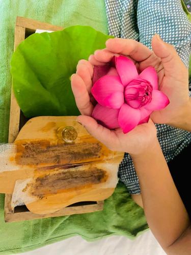 a person holding a pink flower in a wooden box at Zensigiri Ayurveda Wellness Homestay in Sigiriya