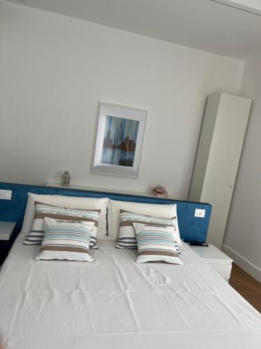 a white bed with pillows and a blue headboard at Dionisio 7 in Pescara
