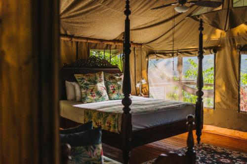 a bedroom with a four poster bed with a ceiling fan at Colina Secreta - Glamping and Villas in Puerto Viejo