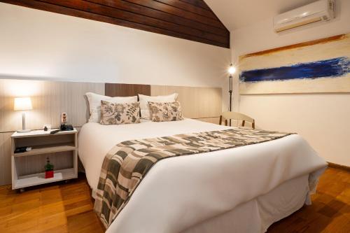 a bedroom with a large white bed and a table at Pousada Apple House Campos do Jordao in Campos do Jordão