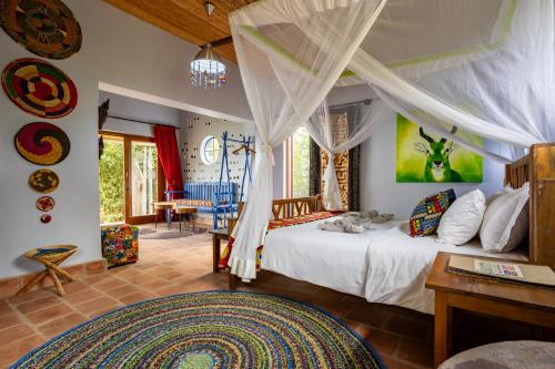 a bedroom with a bed and a table in a room at Chameleon Hill Forest Lodge in Bwindi