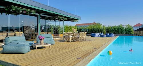a deck with chairs and a swimming pool with a table at Hannover - PHIL & MAX Hotels und Apartments Messe in Hannover