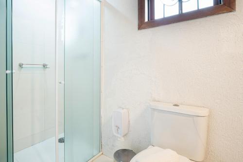 a bathroom with a toilet and a glass shower at Pousada Apple House Campos do Jordao in Campos do Jordão