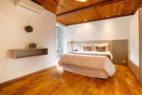 a bedroom with a large bed and a wooden ceiling at Pousada Apple House Campos do Jordao in Campos do Jordão