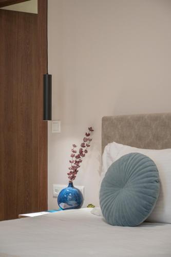 a blue vase sitting on top of a bed with a pillow at IRA - ΗΡΑ Hotel in Kalamata