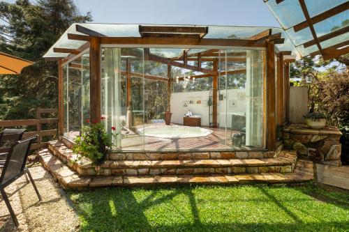 a glass house with a tub in a yard at Pousada Apple House Campos do Jordao in Campos do Jordão