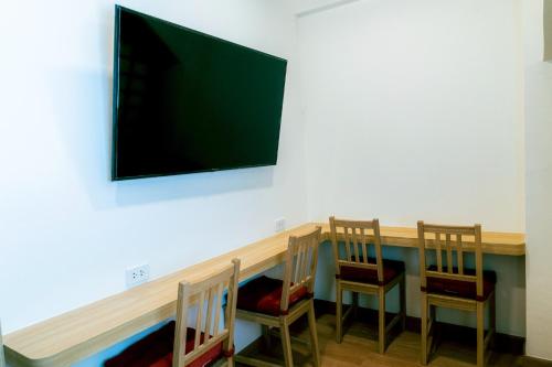 a table with two chairs and a television on a wall at Hakotel in Bang Rak