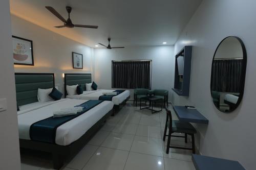 a hotel room with two beds and a mirror at The Lotus Park in Srikalahasti