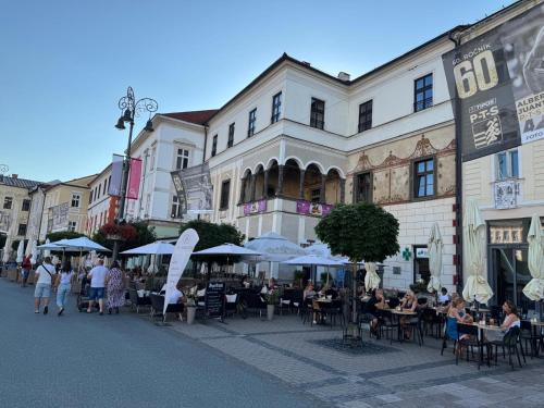 a group of people sitting at tables in front of buildings at ALURE RESIDENCES 11 - 24h self check-in & private parking next to the apartment building included, CITY CENTER right on SNP Square in a quiet passage, new building, best deal in town in Banská Bystrica