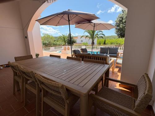 a wooden table with chairs and umbrellas on a patio at La FINCAD4 entre plages et Forêt in Son Parc