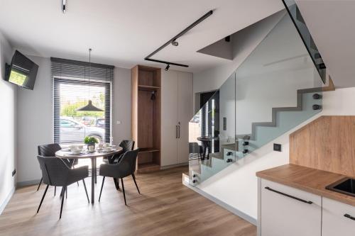 a dining room with a table and chairs and a staircase at Balice Apartamenty Premium - by Upstairs in Cholerzyn