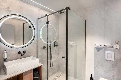 a bathroom with a shower and a sink and a mirror at Balice Apartamenty Premium - by Upstairs in Cholerzyn