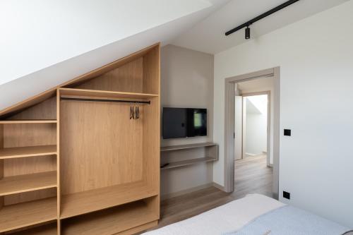 a room with a bed and a tv and a closet at Balice Apartamenty Premium - by Upstairs in Cholerzyn